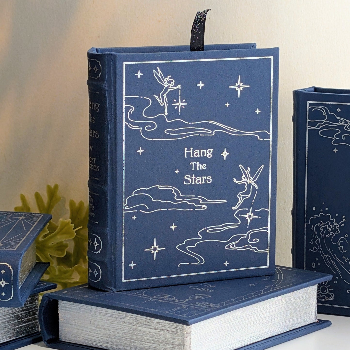 Decorative blue book shaped box with celestial design and text on a neutral background